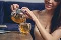 Joyful young woman pouring herbal tea into glass cup Royalty Free Stock Photo