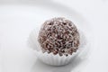 Close up on a chocolate and coconut rum ball on a white plate Royalty Free Stock Photo