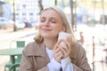 Close up of cheerful blond woman, holding cup of coffee, drinking tea in street outdoor cafe, smiling with happy face Royalty Free Stock Photo