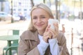 Close up of cheerful blond woman, holding cup of coffee, drinking tea in street outdoor cafe, smiling with happy face Royalty Free Stock Photo