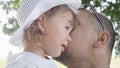 CLOSE UP: Cheerful daddy whispering a secret into innocent baby girl`s ear during their fun walk down picturesque tree avenue.