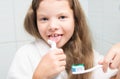 Close-up, a cheerful girl with long hair, holding a toothbrush in her hand and fooling around, trying to taste the paste Royalty Free Stock Photo