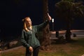 Close-up of a cheerful girl makes a selfie photo on a mobile phone on a night city street. Portrait of happy woman Royalty Free Stock Photo