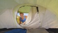 CLOSE UP: Cheerful male tourist opens tent and enters during outdoor adventure