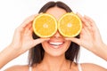 Close up of cheerful woman holding two halves of orange near eyes Royalty Free Stock Photo