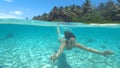 CLOSE UP: Cheerful woman squints while diving in the crystal clear Pacific ocean Royalty Free Stock Photo