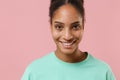 Close up of cheerful young african american woman girl in green sweatshirt posing isolated on pastel pink wall