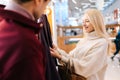 Close-up of cheerful young couple choosing clothes together at clothing shop in shopping center. Blonde woman choosing Royalty Free Stock Photo