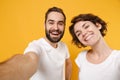 Close up of cheerful young couple friends bearded guy girl in white t-shirts isolated on yellow orange wall background Royalty Free Stock Photo