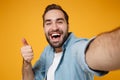 Close up of cheerful young man in casual blue shirt posing isolated on yellow orange wall background. People lifestyle Royalty Free Stock Photo