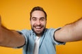 Close up of cheerful young man in casual blue shirt posing isolated on yellow orange wall background, studio portrait Royalty Free Stock Photo