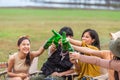 Close up cheering with beer bottle. Group of young Asian friends party on vacation enjoy drinking at camping lake side. hands Royalty Free Stock Photo