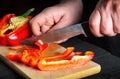 Close-up of chef or cook hands cutting peppers on a cutting board. Professional preparation of salad in the kitchen in a Royalty Free Stock Photo