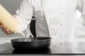 Close up of chef hand pouring sauce from gravy bottle into frying pan at commercial kitchen. Royalty Free Stock Photo