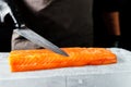 Close-up of chef hand prepared to cooking fresh salmon fillet, black background