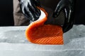 Close-up of chef hand prepared to cooking fresh salmon fillet, black background