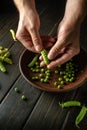 Close-up of the chef hands on the kitchen table peeling green pea pods. Organic peasant food after harvest. Peas in a bowl Royalty Free Stock Photo