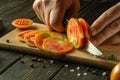 Close-up of a chef hands with a knife cutting a tomato into small pieces for a vegetable salad. Work environment on the kitchen Royalty Free Stock Photo