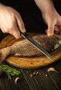 Close-up of the chef hands with a knife on kitchen table before cleaning carp. Cooking a fish dish on the kitchen table Royalty Free Stock Photo