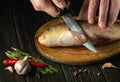 Close-up of the chef hands with a knife on the kitchen table before cleaning the carp. Cooking a fish dish on the kitchen table Royalty Free Stock Photo