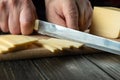 Close-up of a chef hands with a knife slicing cheese on a cutting board in a restaurant kitchen. Preparing dairy food for Royalty Free Stock Photo