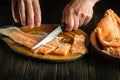 Close-up of a chef hands with knives while cutting or cleaning fresh red fish on a kitchen cutting board before preparing a fis