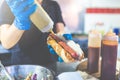 Man holding hot dog and adding mustard. Street fast food vendor concept Royalty Free Stock Photo