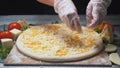 Close-up of chef`s hands adding cheese in four cheeses pizza on a wooden board. Frame. Delicious pizza preparation Royalty Free Stock Photo