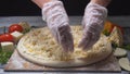 Close-up of chef`s hands adding cheese in four cheeses pizza on a wooden board. Frame. Delicious pizza preparation Royalty Free Stock Photo