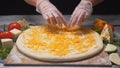 Close-up of chef`s hands adding cheese in four cheeses pizza on a wooden board. Frame. Delicious pizza preparation Royalty Free Stock Photo