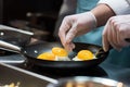 close-up of chef& x27;s hands frying eggs in a skillet