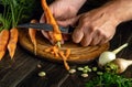 Close-up of a chef hands with a knife while peeling carrots. The concept of cooking vegetarian food or vegetable soup for lunch Royalty Free Stock Photo