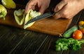 Close-up of a chef's hands peeling ripe sweet peppers with a knife before slicing them on the kitchen table. Vegetable menu Royalty Free Stock Photo