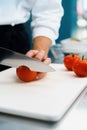 Close-up of a chef slicing tomato in a professional restaurant kitchen Royalty Free Stock Photo