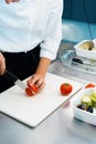 Close-up of a chef slicing tomato in a professional restaurant kitchen Royalty Free Stock Photo