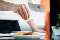 Close-up of a chef sprinkling French omelet with finely chopped herbs in a professional kitchen Royalty Free Stock Photo