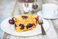 Close up of cherry cake pieces with fresh cherries and a coffee cup over old wood background.