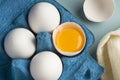 Close-up of chicken fresh eggs in eco-packaging on a blue background. Broken egg with yolk in the shell. Farm natural products. Royalty Free Stock Photo