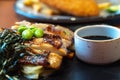 Close up of chicken steaks with cup of sauce on the black plate. Green peas and Japanese seaweed on chicken steaks with white cabb Royalty Free Stock Photo