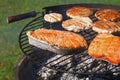 Chicken or turkey burger and salmon steak on grill Royalty Free Stock Photo