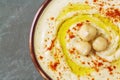 Close up of chickpea hummus decorated with boiled chickpeas, olive oil and paprika.