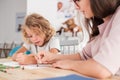 Child with an autism spectrum disorder and the therapist by a table drawing with crayons during a sensory