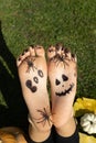 close up of a child bare feet with a scary face drawn and inscription boo in black paint