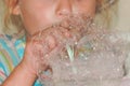 Close up child blows bubbles through a plastic tube made of soap foam, kids fun games .