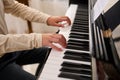 Close-up of a child boy touching piano keys with fingers, performs a musical composition while playing grand piano