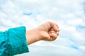 Close up of fisted child hand raised up over blue sky and clouds. Gesture Royalty Free Stock Photo