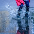 Close up child girl with rain boots jumping in puddles after rain. Childhood, laisure, happiness concept Royalty Free Stock Photo