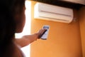 Close-up of child hand adjusting air conditioner with remote control on orange background. Royalty Free Stock Photo