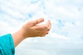 Close up of child hand raised up over blue sky and clouds background. Gesture Royalty Free Stock Photo