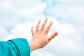 Close up of child hand raised up over blue sky and clouds background. Gesture Royalty Free Stock Photo